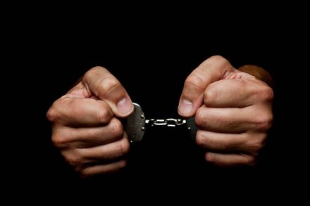 Handcuffes on man hand’s on black background